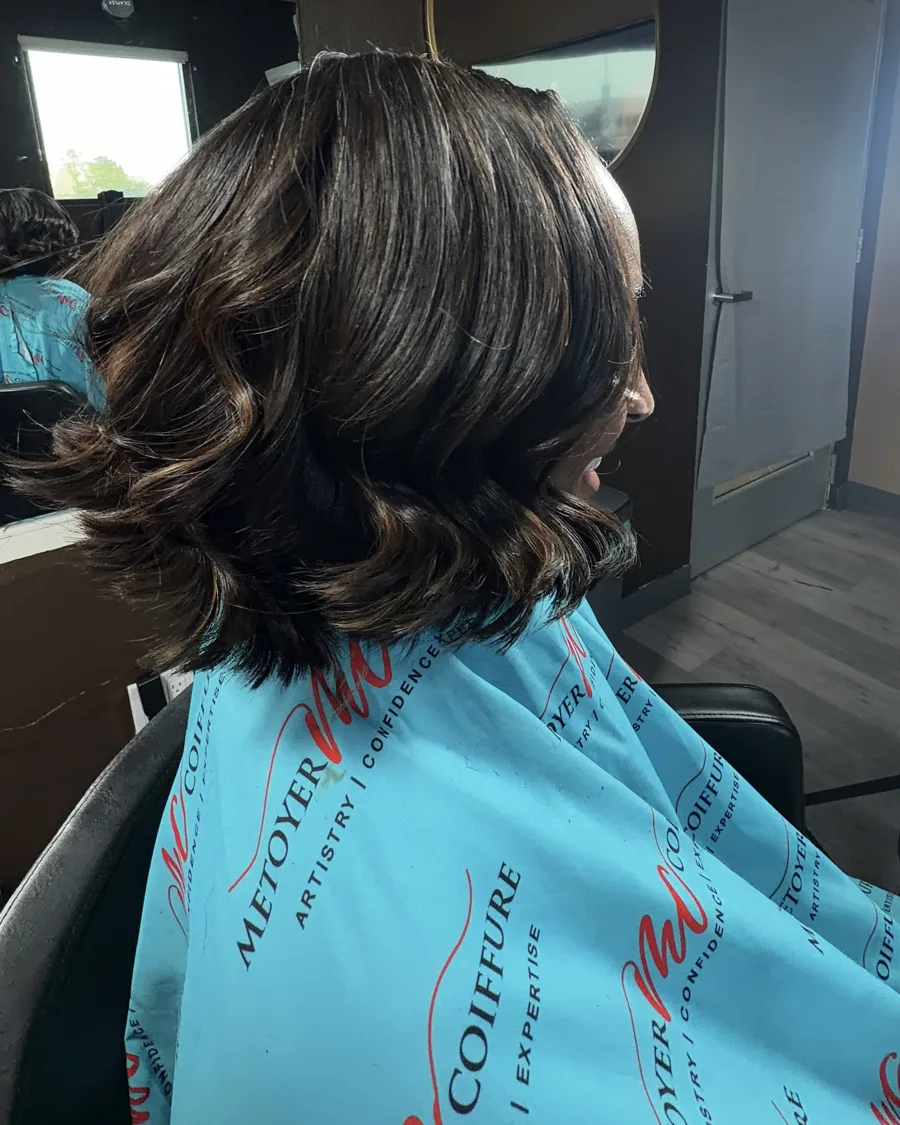 Bouncy bob silk press with soft curled ends, client wearing a Metoyer Coiffure cape